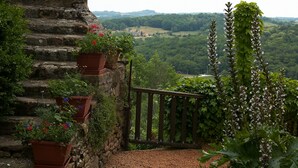 Un edificio de piedra con puerta de madera, escalones que conducen a un sendero de grava y vistas a un paisaje verde.