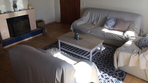 A living room with a sofa, a coffee table, a fireplace, and a patterned rug. - 3-bedroom Villa with private swimming pool (Porches)