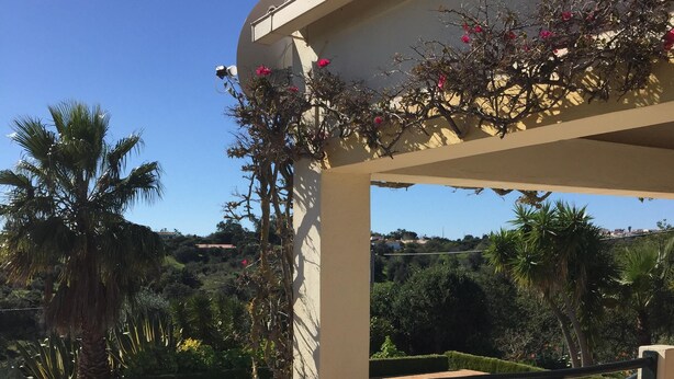 A poolside area with wicker chairs and a table, overlooking a swimming pool and lush greenery. - 3-bedroom Villa with private swimming pool (Porches)