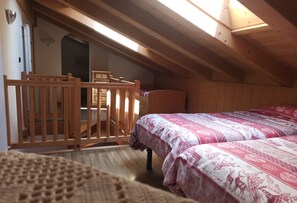 A cozy attic bedroom with wooden beams, a slanted ceiling, and a bed with patterned bedding.