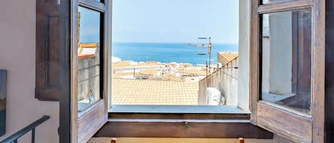 A room with a wooden bed and a window with open shutters.