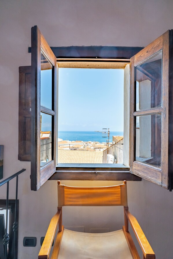 A room with a wooden bed and a window with open shutters.