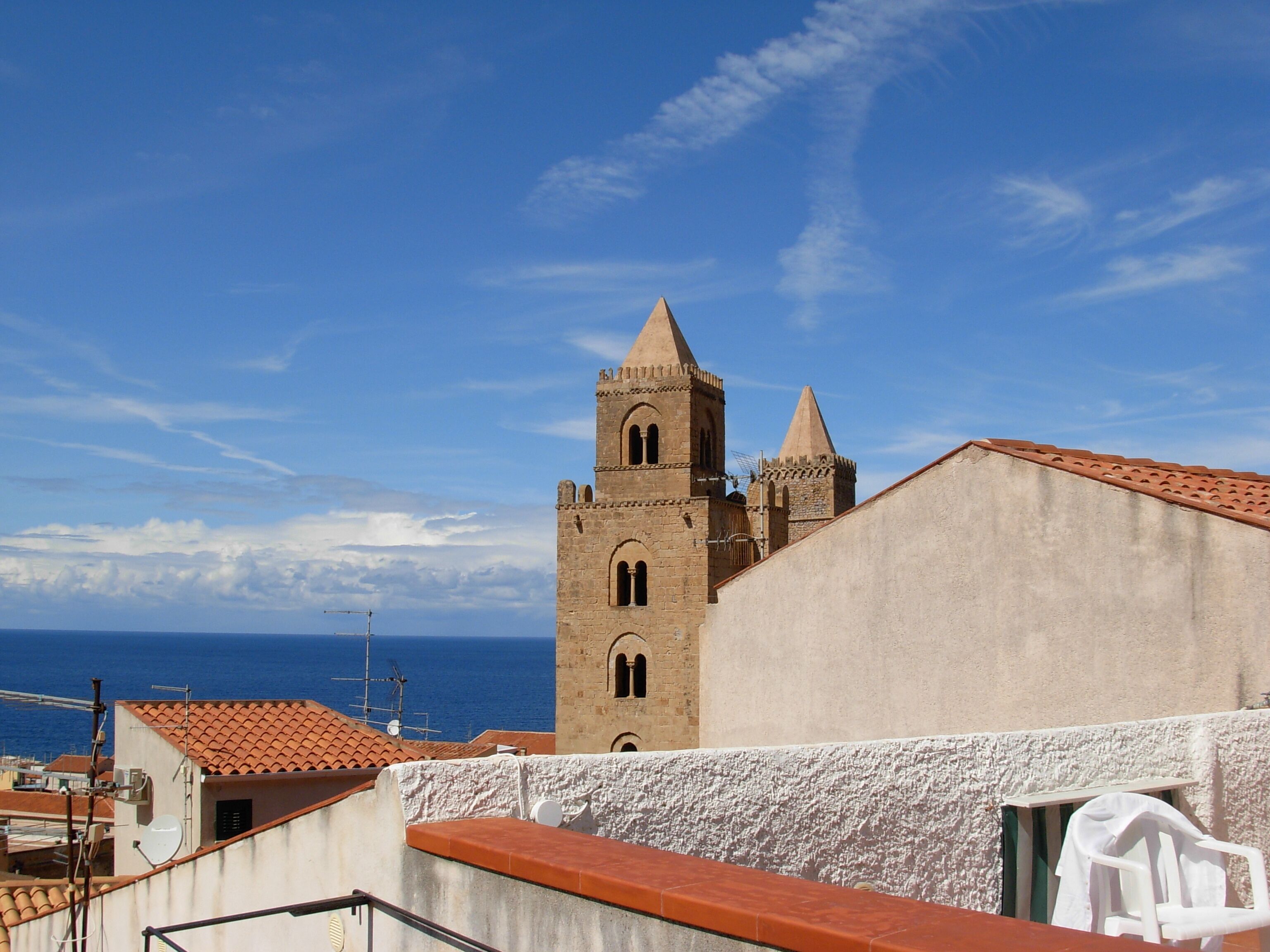 Ein Gebäude mit einem Turm, einem Balkon und Blick auf das Meer.
