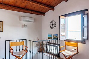 A room with a wooden ceiling, a wall-mounted air conditioner, a clock, and two folding chairs.