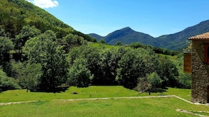 A rural landscape with a stone building, lush greenery, and mountains in the background. - Rural house in an impressive natural setting! Up to 10 people (Montagut I Oix)