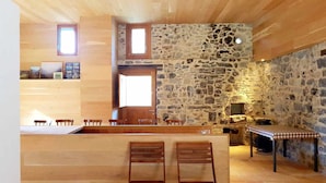 A rustic kitchen with wooden walls, a stone accent wall, and a wooden counter with bar stools. - Rural house in an impressive natural setting! Up to 10 people (Montagut I Oix)