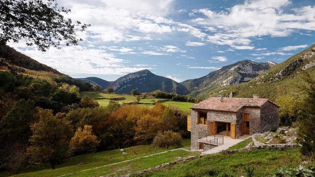 A stone house with a tiled roof, surrounded by a lush green landscape and mountains in the background. - Rural house in an impressive natural setting! Up to 10 people (Montagut I Oix)