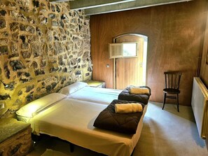 A room with two beds, a stone wall, a wooden door, and a chair. - Rural house in an impressive natural setting! Up to 10 people (Montagut I Oix)