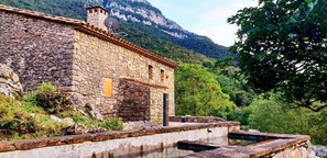 A stone building with a rustic appearance, a small window, and a satellite dish. - Rural house in an impressive natural setting! Up to 10 people (Montagut I Oix)