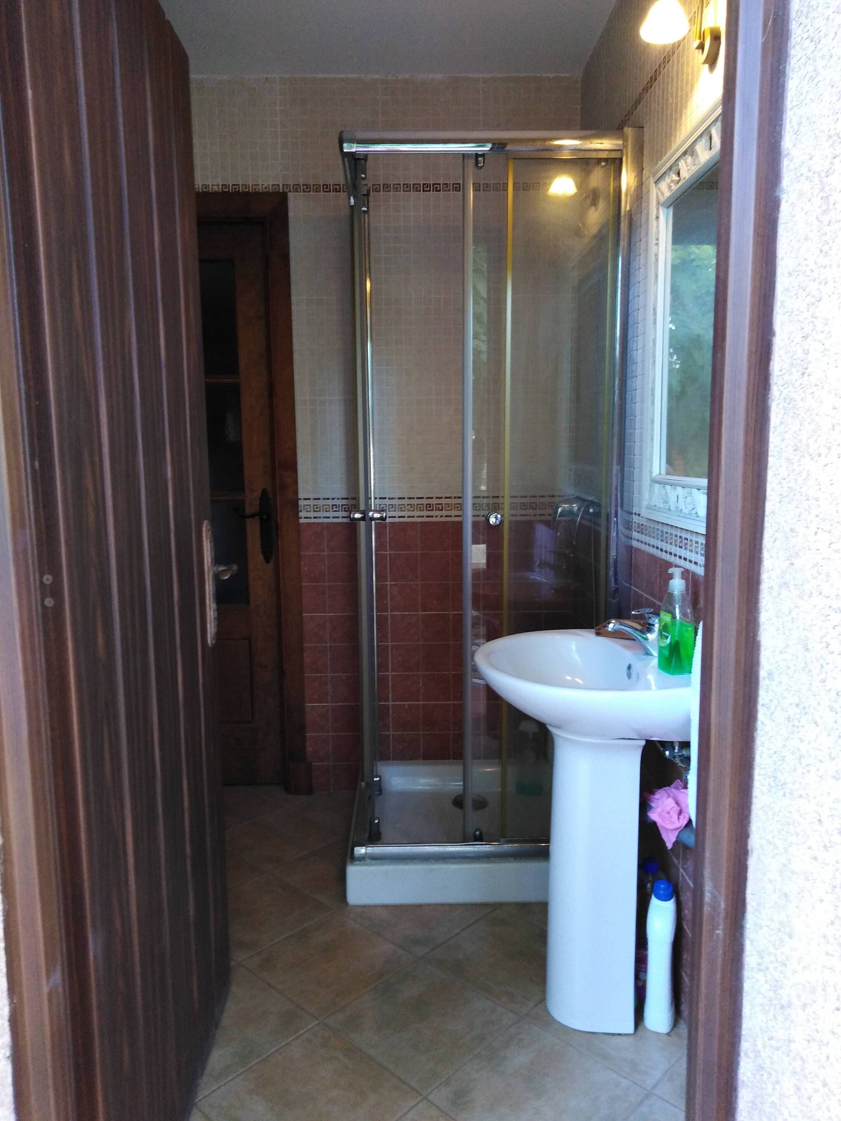 A bathroom with a glass shower enclosure, a white sink, and a mirror.