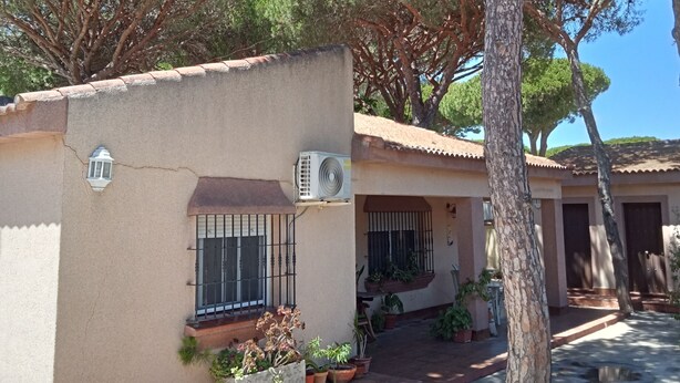 A house with a tiled roof, a small porch, and a window with bars. - Villa with private pool, barbecue and WIFI near the beach. (Chiclana de la Frontera)