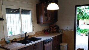 A kitchen with a dishwasher, double sink, and wooden cabinets. - Villa with private pool, barbecue and WIFI near the beach. (Chiclana de la Frontera)
