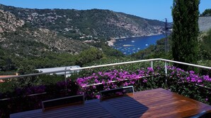 A terrace with a table and chairs, overlooking a coastal landscape with hills and a body of water. - Loft in Aiguablava beach. Costa Brava. With private garden and sea views. (Begur)