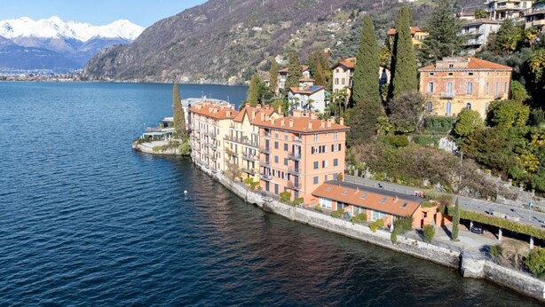Un hôtel situé au bord de l’eau, composé de plusieurs bâtiments, doté d’une jetée en pierre et offrant une vue imprenable sur les montagnes et un lac.