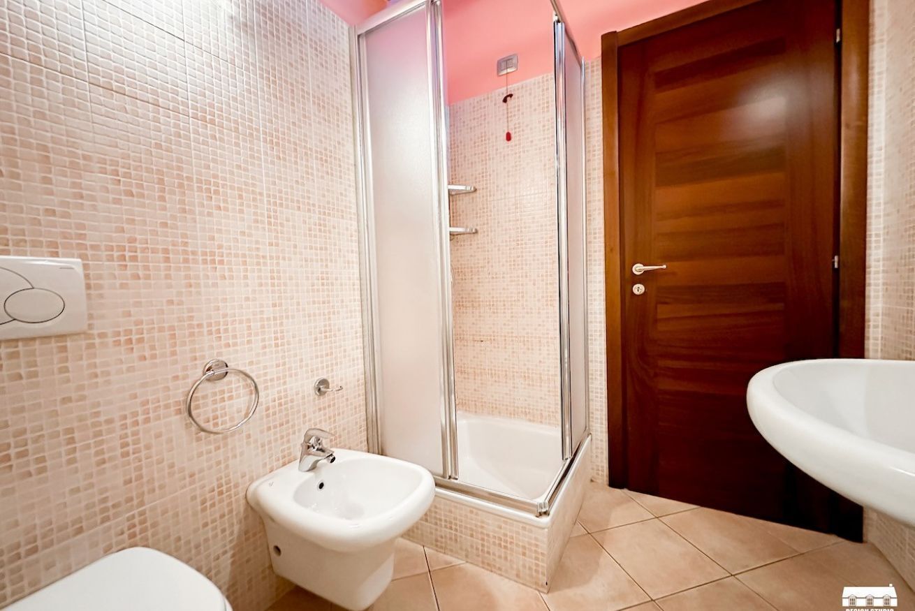 Een badkamer met een douche, toilet en wastafel.