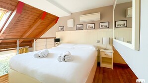 Une chambre avec un grand lit, un plafond en bois et une vue sur l’extérieur.