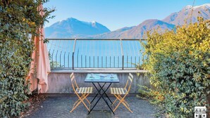 Une terrasse avec une table et des chaises, d’où l’on peut admirer une montagne et un plan d’eau.