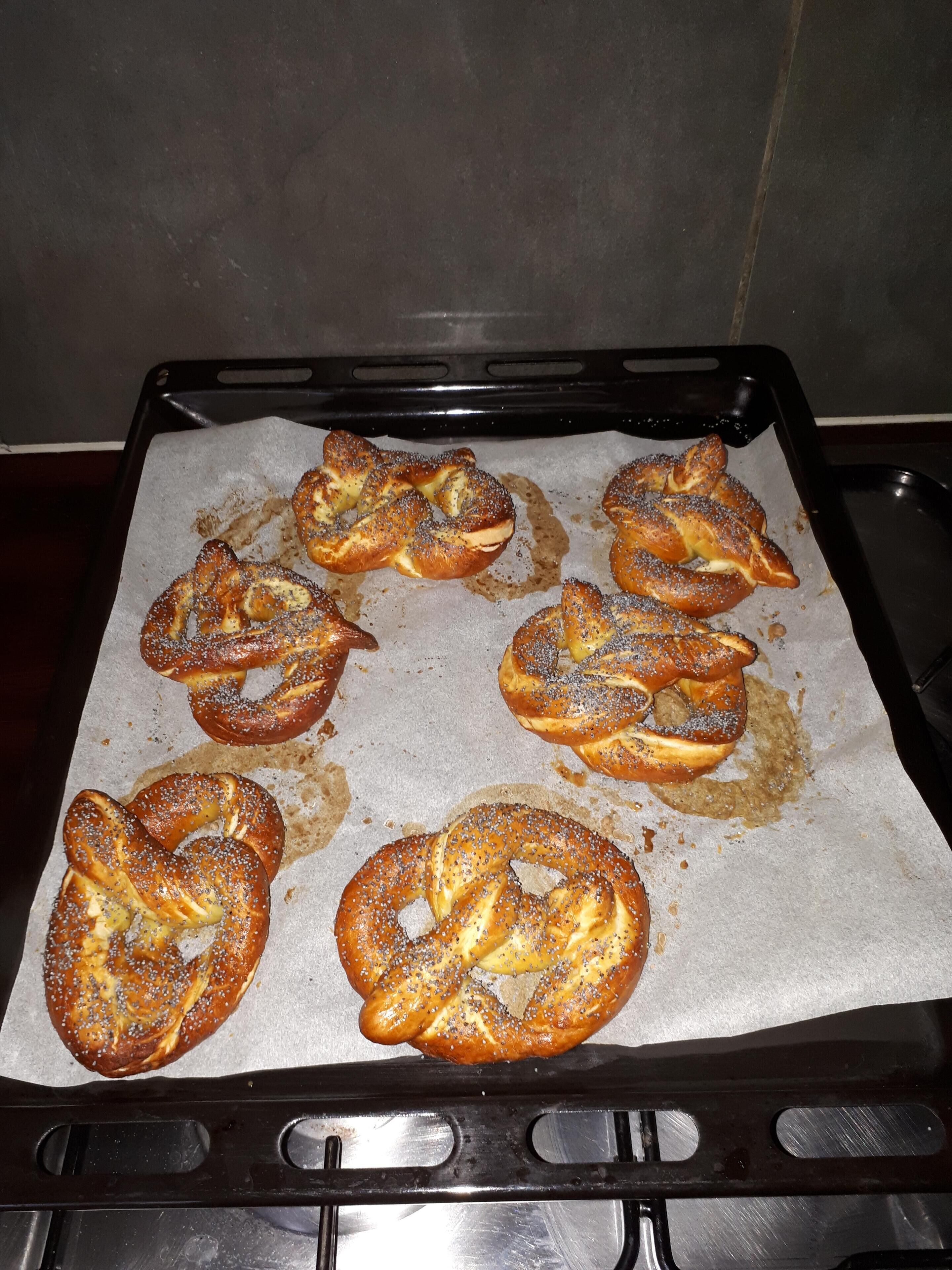Uma assadeira com vários pretzels sobre papel vegetal.