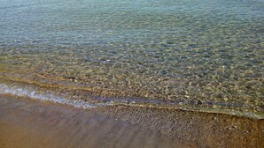 Una spiaggia con acque limpide e poco profonde e una battigia sabbiosa.