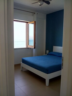 Un dormitorio con cama, ventana y ventilador de techo.