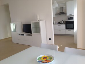 Cozy living space with a dining table, flat-screen TV, and fully equipped kitchen.