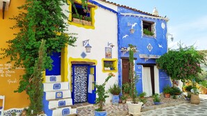 Un edificio con pareti esterne blu e gialle, piante in vaso e pavimento piastrellato.