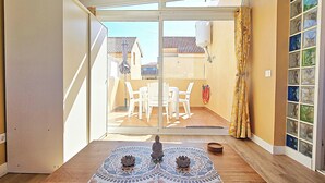 Ein Zimmer mit einer Schiebetür, die auf eine Terrasse mit Tisch und Stühlen führt.