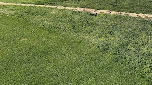 A golf course with a clear view of the ocean and a distant city skyline.