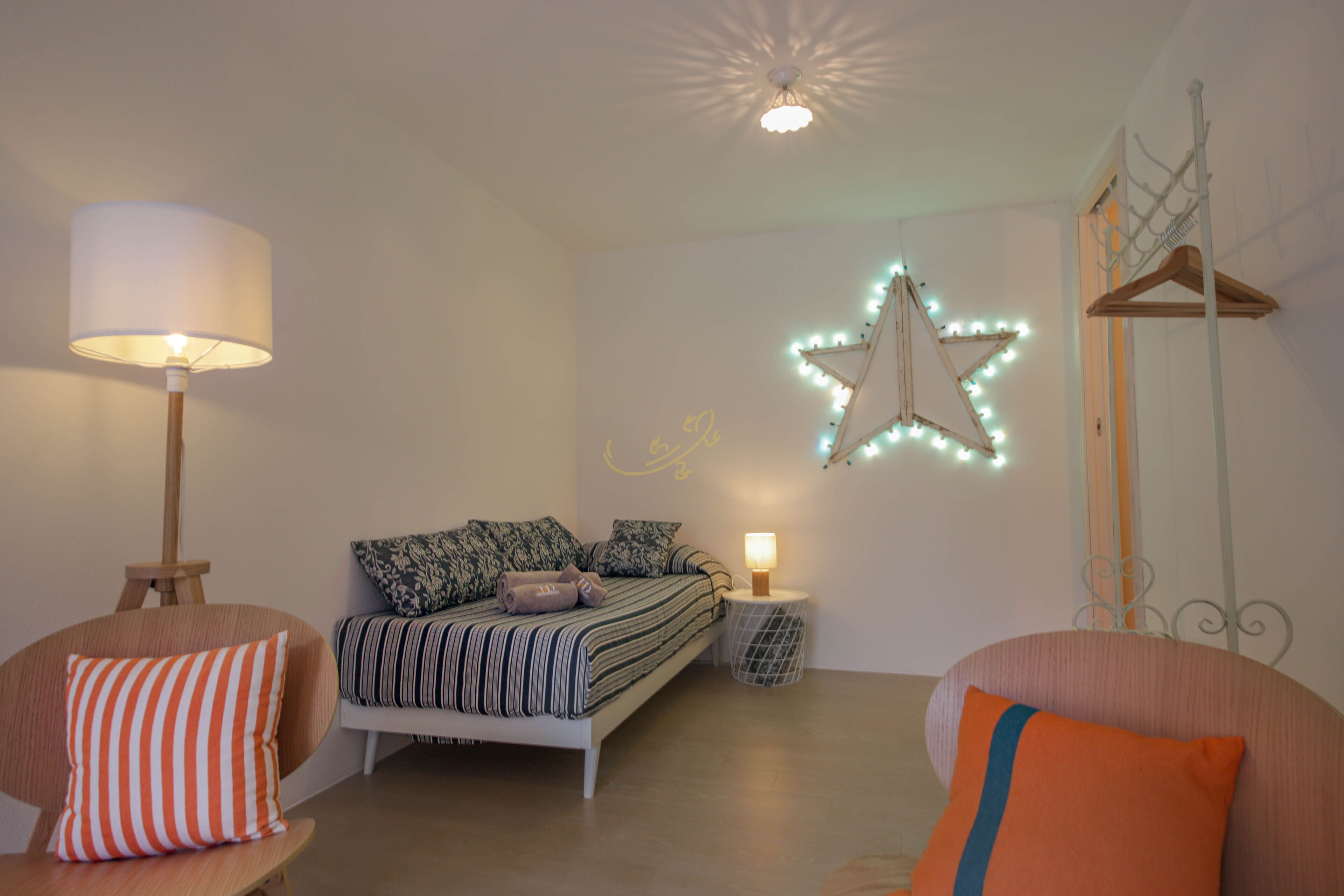 A bedroom with a bed, bedside tables, a hanging light fixture, and a star-shaped light decoration.
