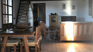 Un interior rústico con una mesa de comedor de madera, sillas, una escalera y un sofá.
