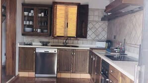 Una cocina con armarios de madera, lavavajillas de acero inoxidable, salpicadero de azulejos y piso de ladrillo.