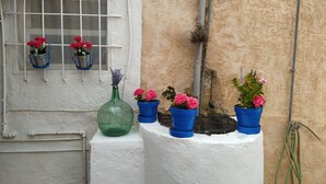 A white wall with a window, potted plants, and a green vase.
