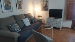 A living room with a sofa, a TV, a small side table, and a chair.
