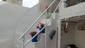 A white staircase with blue flower pots and a small table with a grill.