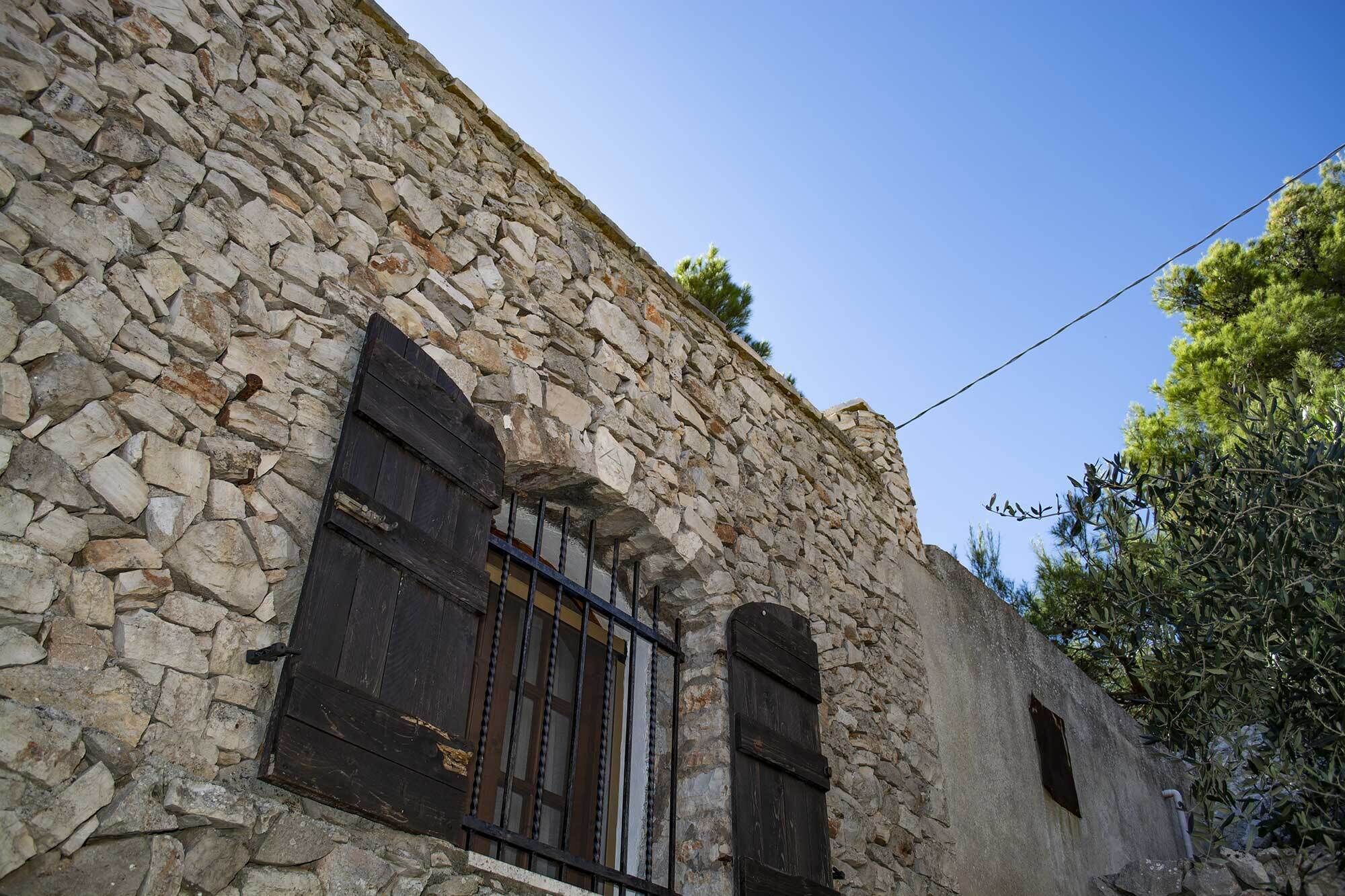 Un bâtiment en pierre doté de fenêtres en arc de cercle et d’une porte en bois.