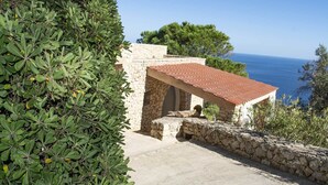 A stone building with a tiled roof overlooking the sea.