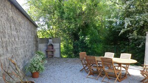 Un patio con una mesa y sillas de madera redondas, rodeado de grava.