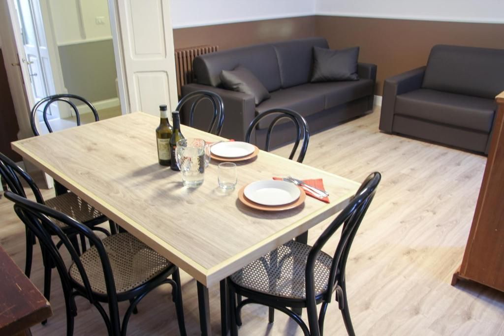 Een eetgedeelte met een houten tafel, zwarte stoelen en een bank op de achtergrond.
