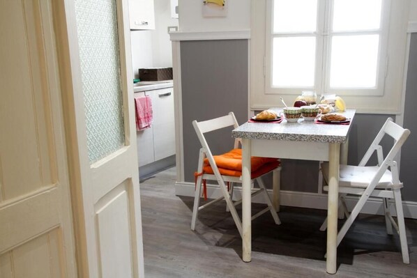 A dining area with a table set for two, chairs, and a window with natural light. - Max Apartment (Verona)