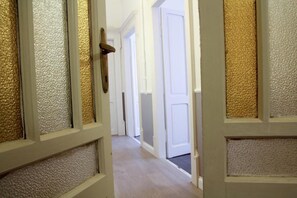 A hallway with white doors and textured panels.