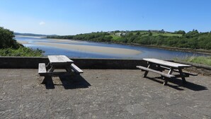 A riverside picnic area with two benches and a stone pavement. - Mullaghduff Thatched Cottage on the Wild Atlantic Way, near Kincasslagh, Donegal (Annagry)