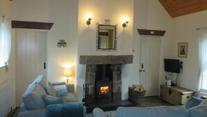 A cozy living room with a fireplace, blue sofas, a television, and a wooden ceiling. - Mullaghduff Thatched Cottage on the Wild Atlantic Way, near Kincasslagh, Donegal (Annagry)