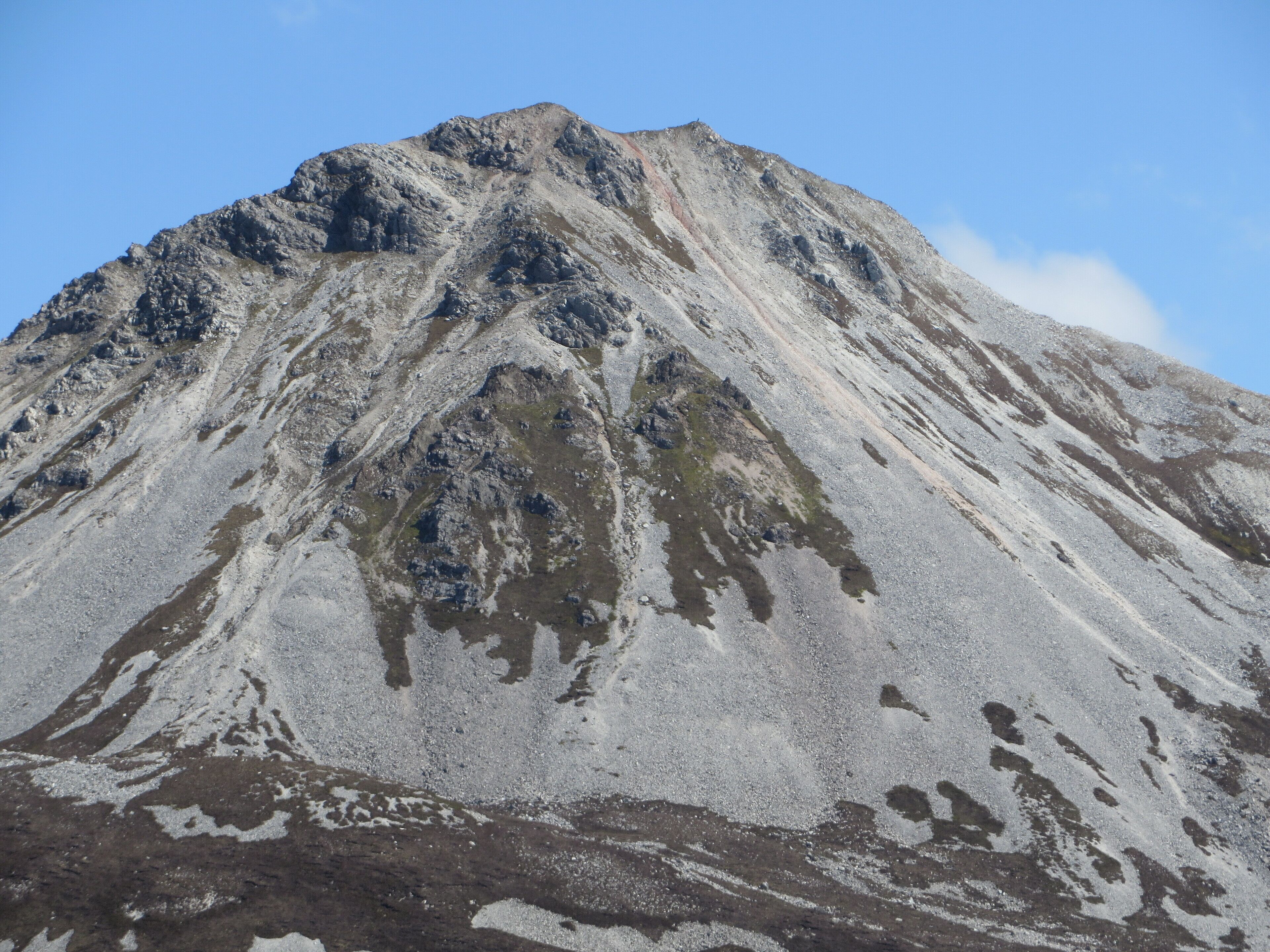 A mountain with a rugged, rocky surface and sparse vegetation.