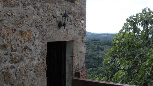 A stone building with a wooden bench and a black door. - Traditional hamlet house with a terrace - NEW: WIFI AVAILABLE (Vals-Les-Bains)