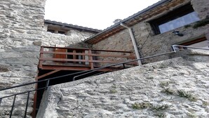 A stone building with a wooden balcony and a metal staircase. - Traditional hamlet house with a terrace - NEW: WIFI AVAILABLE (Vals-Les-Bains)