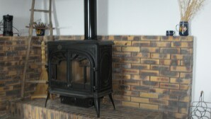 A wood-burning stove with a brick surround, a wooden ladder, and a vase with dried plants on a shelf. - Traditional hamlet house with a terrace - NEW: WIFI AVAILABLE (Vals-Les-Bains)