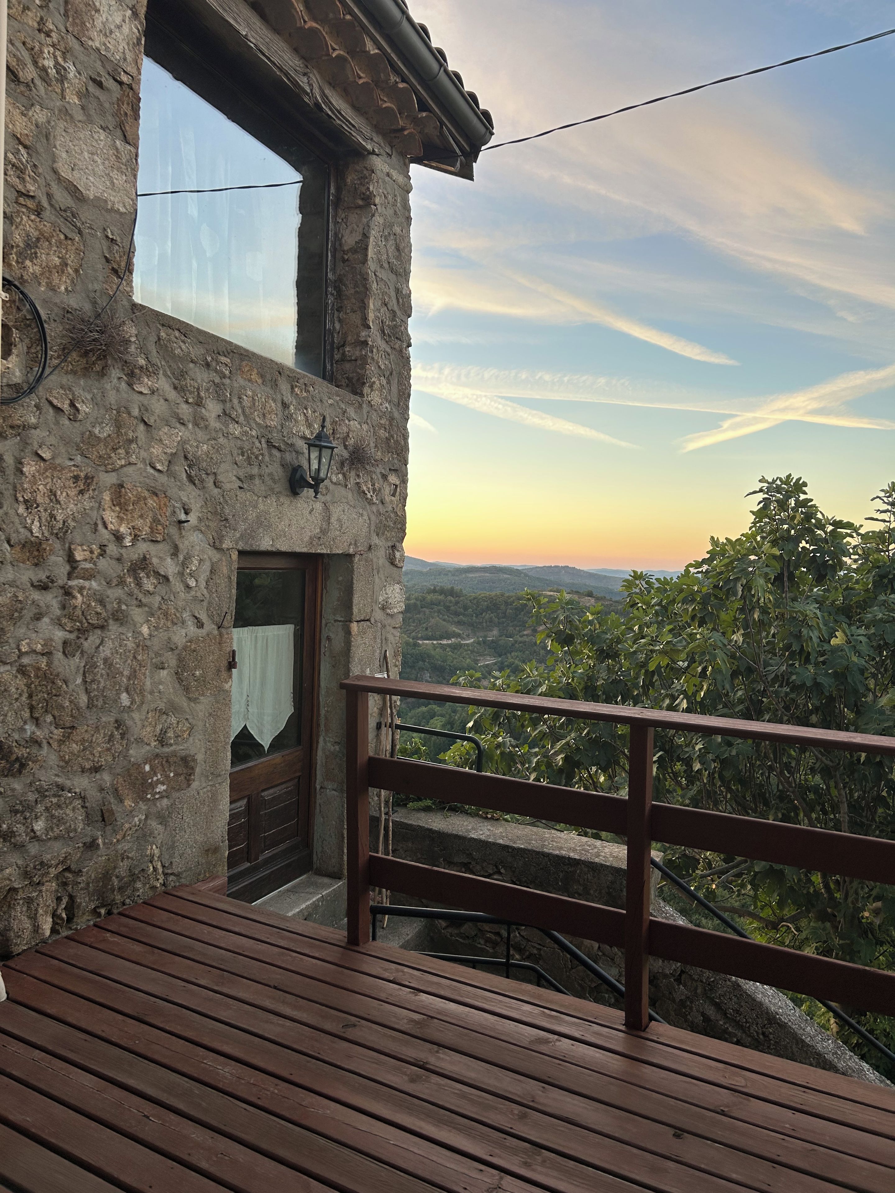 A stone building with a wooden deck and a view of the landscape.