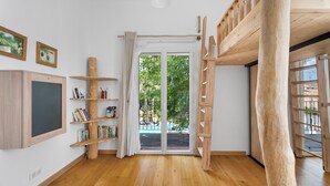 A room with a wooden bunk bed, a bookshelf, a desk, and a large window with a view of greenery. - House with garden (Saint-Cyr-Sur-Mer)