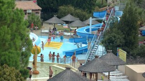A water park with multiple slides and pools, surrounded by thatched-roof structures and palm trees. - House with garden (Saint-Cyr-Sur-Mer)