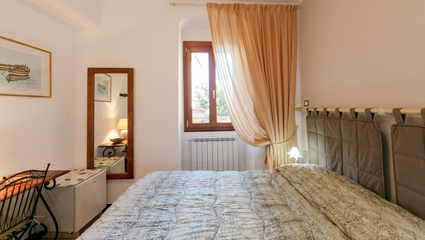 Une chambre à coucher comprenant un lit, un bureau, une chaise, une fenêtre avec des rideaux et un radiateur.